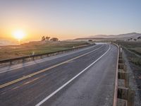 a paved road winds up to the sun as it sets over the ocean in a beautiful landscape