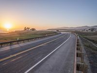 a paved road winds up to the sun as it sets over the ocean in a beautiful landscape