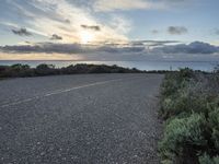 an empty roadway going down to the sea during sunrise or sunset hours in a remote location