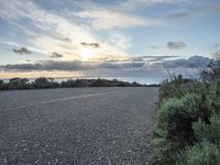 an empty roadway going down to the sea during sunrise or sunset hours in a remote location