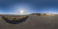 a full view of a deserted street with no traffic on it with the sun reflecting in the lens