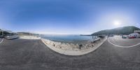 a 360 - degree view of a town by the water with the sun in the sky