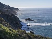 a scenic view of the ocean, coast, and cliffs on a cliff road and in the foreground the water is mostly clear