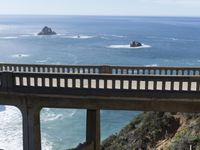 a bridge crosses over a beach towards the ocean and mountains near an ocean view area