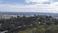 a person taking a picture with her camera overlooking the city from a hillside in the distance