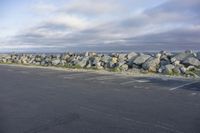 a gravel wall along the ocean is shown in this photo and is shown above an empty parking lot