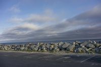 a gravel wall along the ocean is shown in this photo and is shown above an empty parking lot