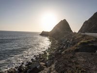 the sun setting over an island with waves coming up from it's shoreline