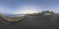 a fish eye lens view of an empty street next to the ocean in a small town