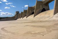 a close up of some concrete in the sand with water and a bridge in the background