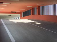 an empty parking garage with red walls and concrete floors and painted white lines in white