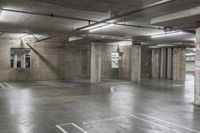 an empty parking garage with concrete floors and overhead lightings with no visible signs on the ceiling