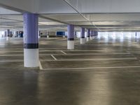 a parking garage with multiple parking spaces, all lined up, and empty white columns