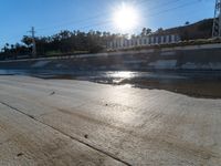 a skateboarder on the street with the sun reflecting in it's waters