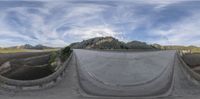 a 360 degree view of a road and hills near a bridge and road in the country