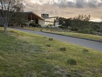 this modern house is on the edge of the grassy hill and the street is empty