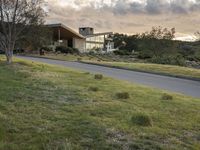 this modern house is on the edge of the grassy hill and the street is empty