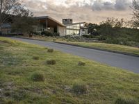 this modern house is on the edge of the grassy hill and the street is empty