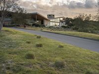 this modern house is on the edge of the grassy hill and the street is empty