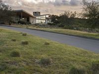 this modern house is on the edge of the grassy hill and the street is empty