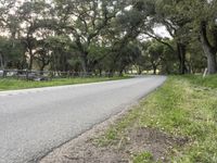 a curve road in a country setting with trees near by and an empty park bench