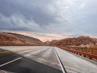 a highway with hills and mountains as seen out the windshield of a car in desert