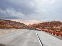 a highway with hills and mountains as seen out the windshield of a car in desert