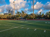 several soccer field in the background with trees and buildings in the distance behind them, the sky has some white clouds