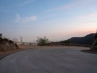 a person on a skateboard rides down the side of a mountain road at dusk