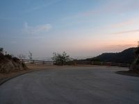 a person on a skateboard rides down the side of a mountain road at dusk