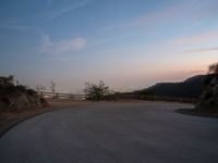 a person on a skateboard rides down the side of a mountain road at dusk