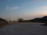 a person on a skateboard rides down the side of a mountain road at dusk