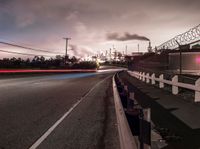 a highway with a sky view and two white fire trucks driving down it and smoke billowing into the sky