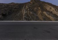 a motorcycle is parked on the side of the road near a mountain top at sunset