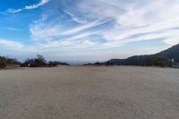 two women sit on a bench on top of a dirt field on a hillside overlooking the horizon