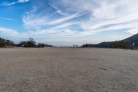 two women sit on a bench on top of a dirt field on a hillside overlooking the horizon