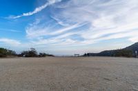 two women sit on a bench on top of a dirt field on a hillside overlooking the horizon