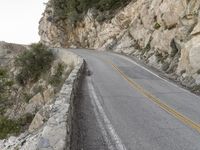 the road runs along a cliff and the car is parked in the street under it