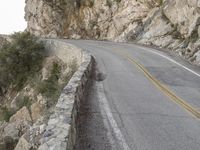 the road runs along a cliff and the car is parked in the street under it