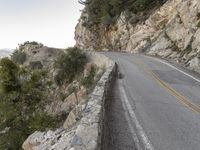 the road runs along a cliff and the car is parked in the street under it