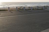 an empty road near a beach and waves as well as cars on the sand and houses on the beach