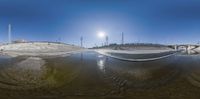 a reflection of a snowboarder doing tricks on a snowy slope while another skateboarder does tricks nearby