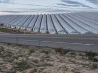 large farm area with a road leading to it and a sky above it with wispy clouds