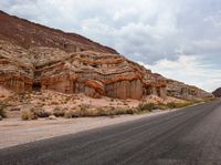 a road in the desert and rocky area by the mountains with rocks that have been carved into it