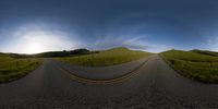 the camera view shows a curved road running through green hills and grass and flowers on the side