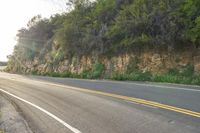 a long road with a rock cliff on the side, which has a yellow strip to show its colors