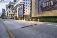 a sidewalk has food and soda on it outside a tall building in the city, which has an advertisement on the wall