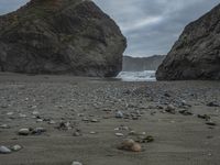 rocks and pebbles on the beach with one lone cow lying next to each other as a stormy sky hangs above the ocean