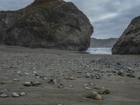 rocks and pebbles on the beach with one lone cow lying next to each other as a stormy sky hangs above the ocean