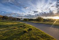 a rural sunset as the sun starts to rise over some land on a road with some grass